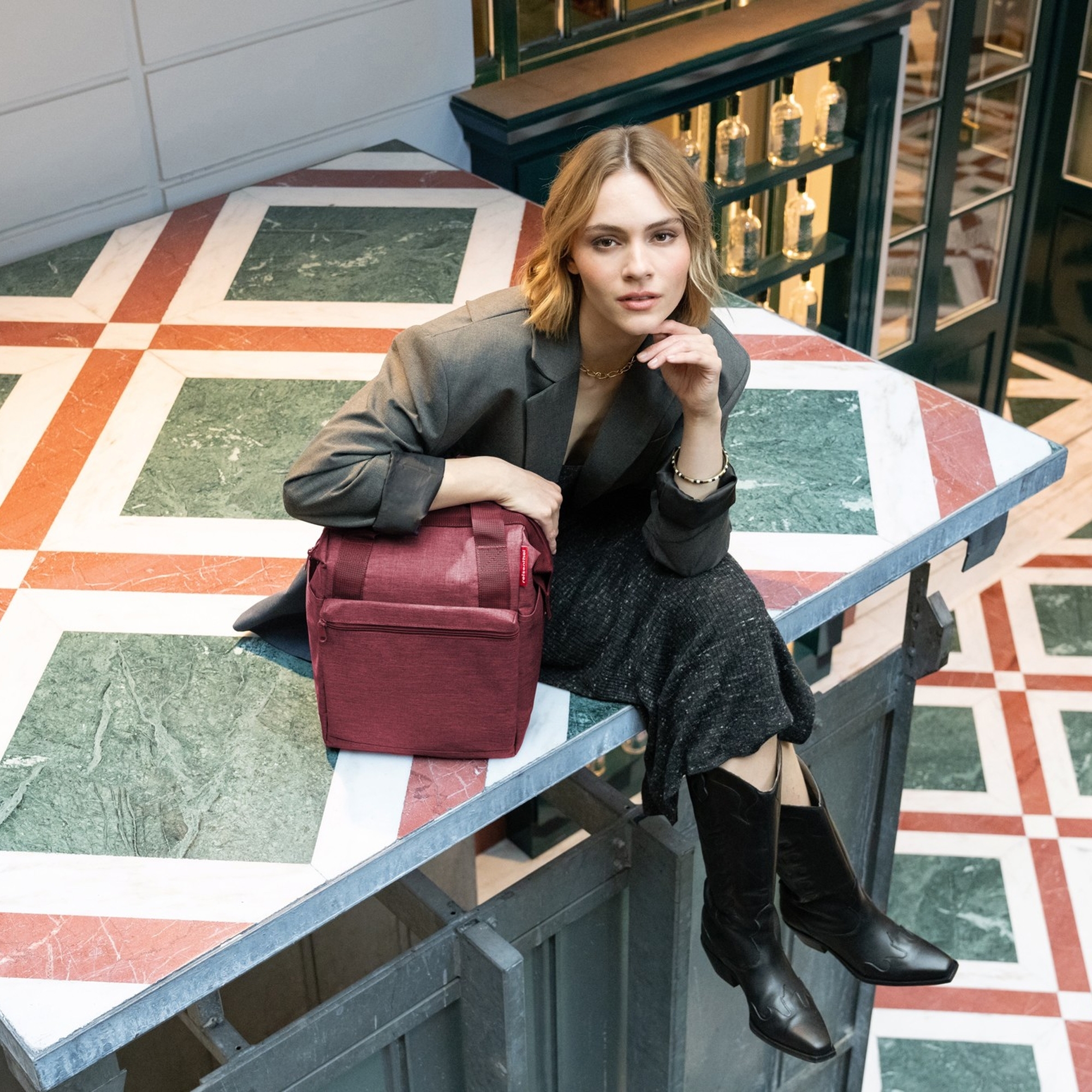 Frau mit roter Umhängetasche auf Marmortisch