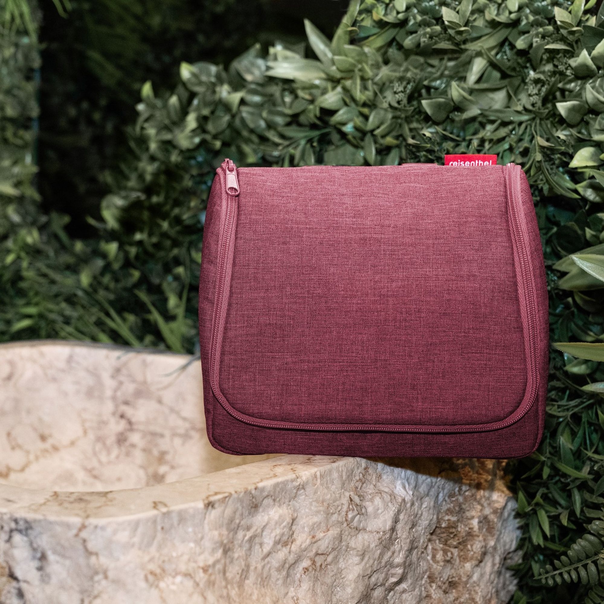 Burgunderrotes Kulturbeutel aus Stoff an Marmorwaschbecken