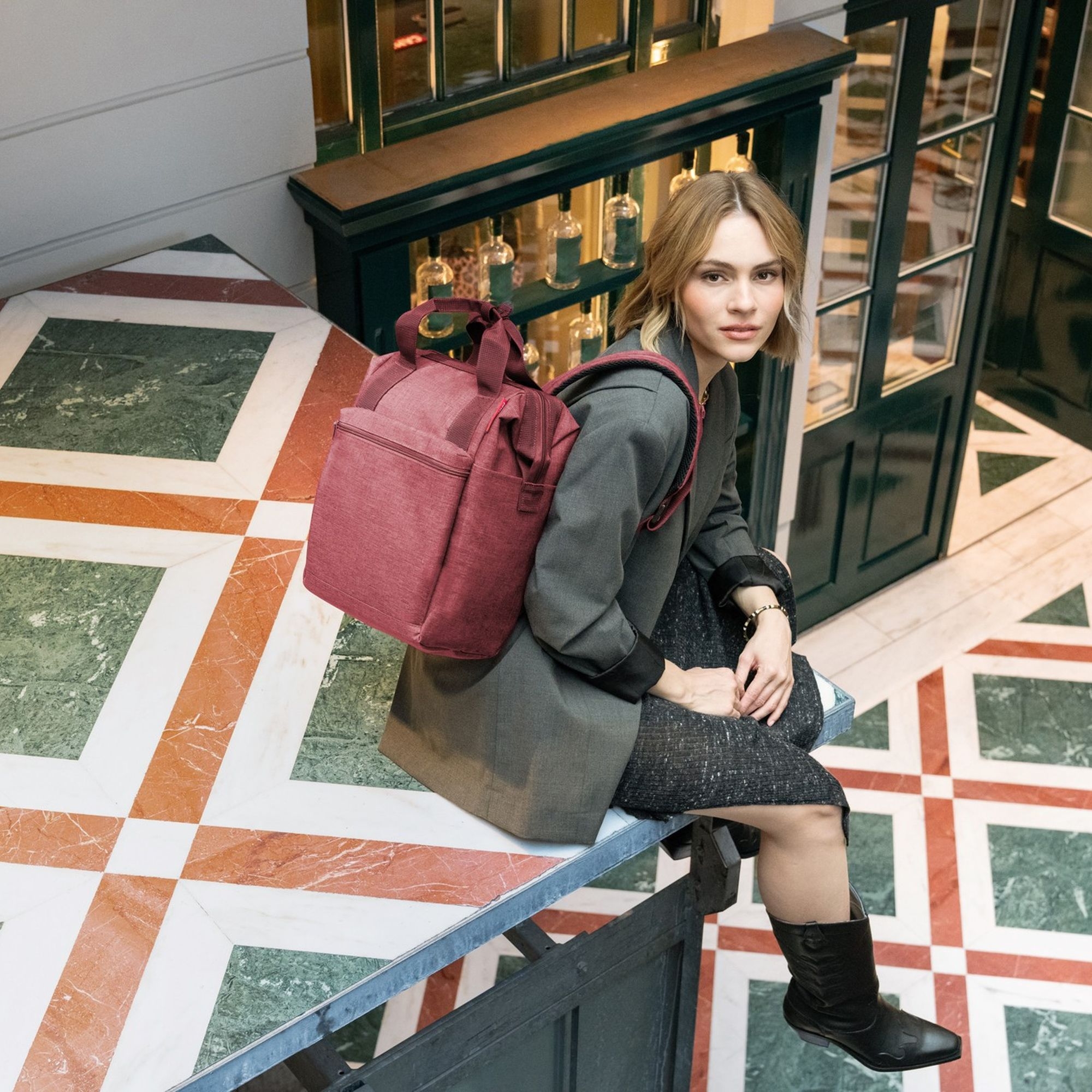 Frau mit weinrotem City-Rucksack im Innenraum