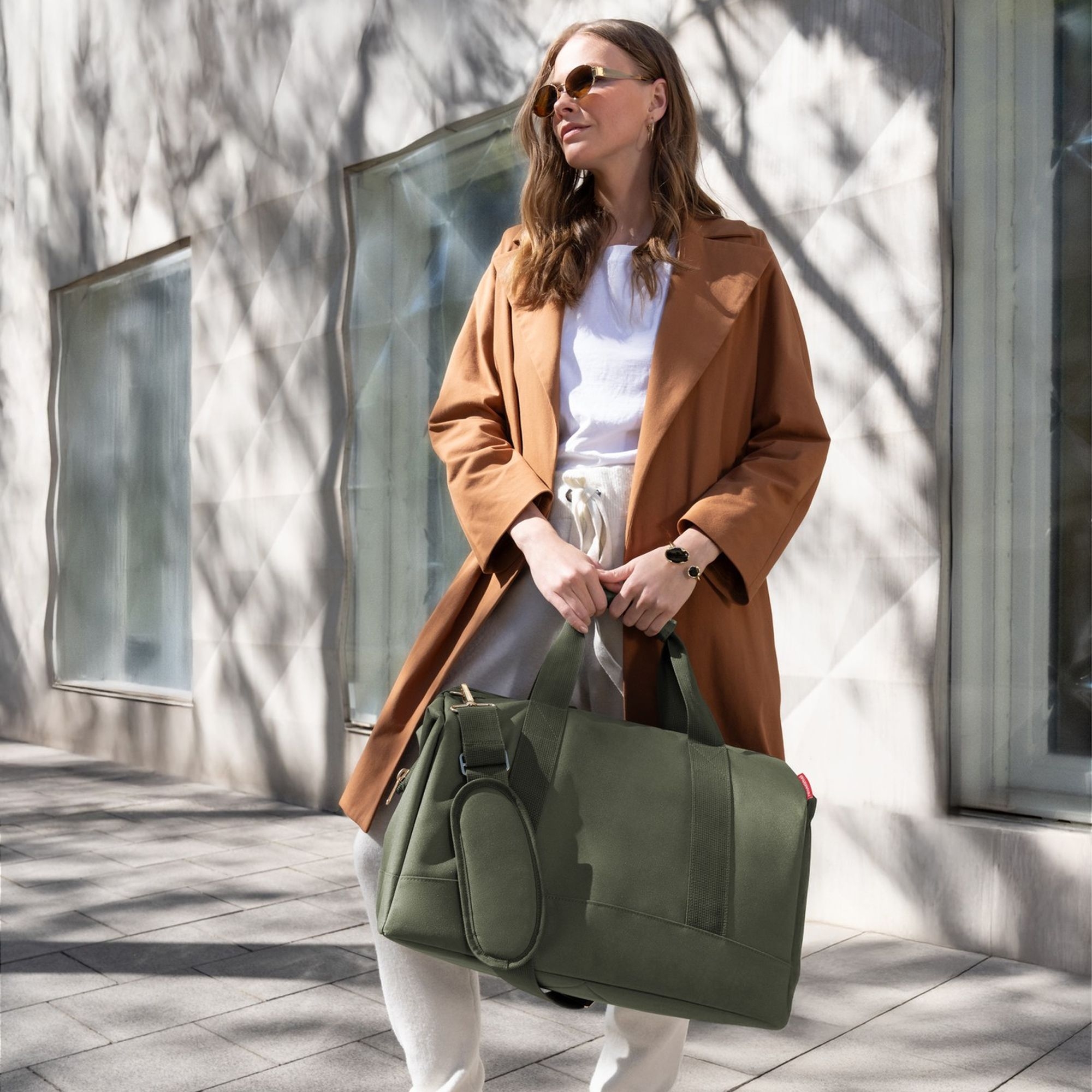 Frau mit olivgrüner Weekender-Tasche im Stadtlook