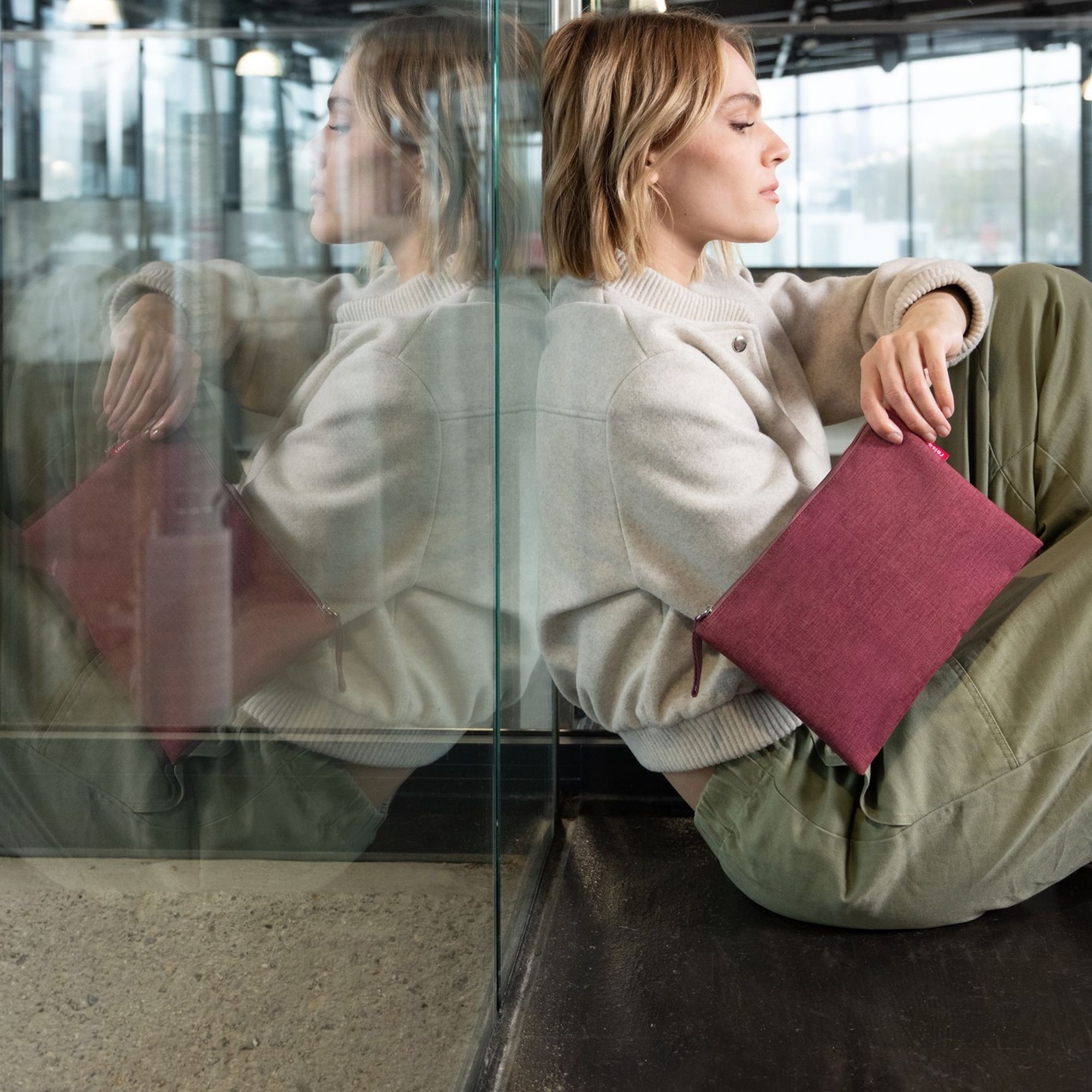 Frau mit beerefarbener Clutch im urbanen Look