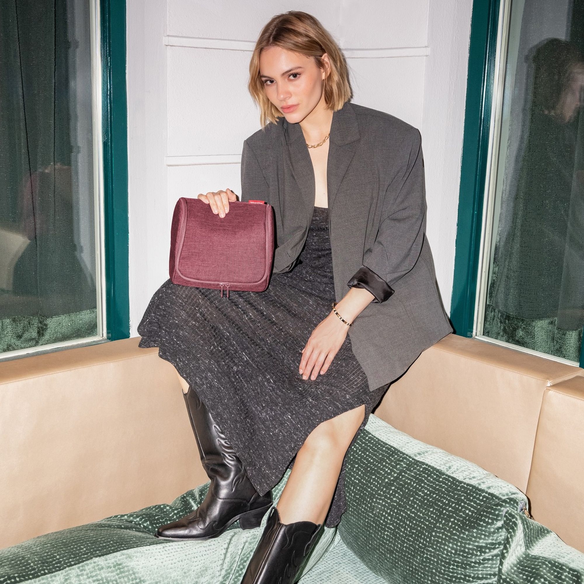 Frau mit grauem Kleid und grauem Blazer hält rote Tasche