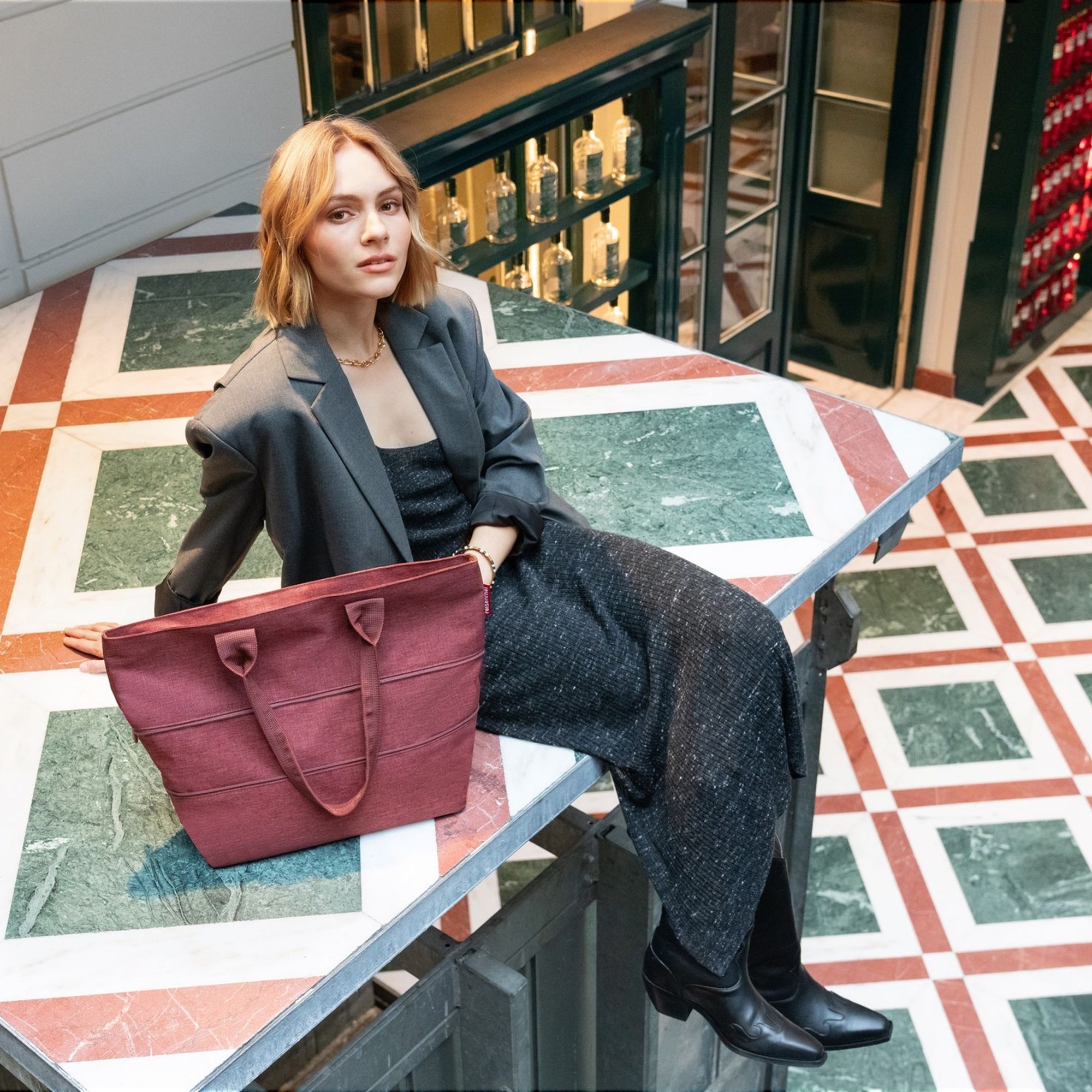 Frau mit bordeauxroter Schultertasche auf Marmortisch