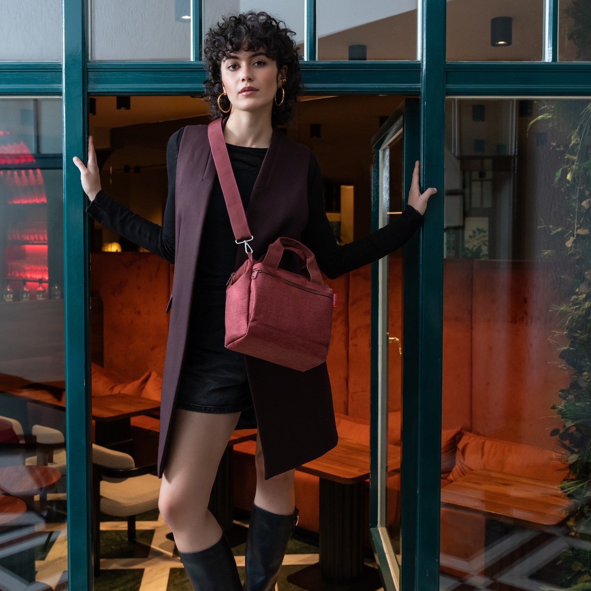 Dame mit eleganter weinroter Umhängetasche im Café